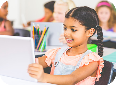 Criança contente em sala de aula segura um tablet