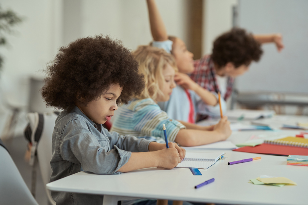 Crianças escrevendo em caderno sobre a mesa